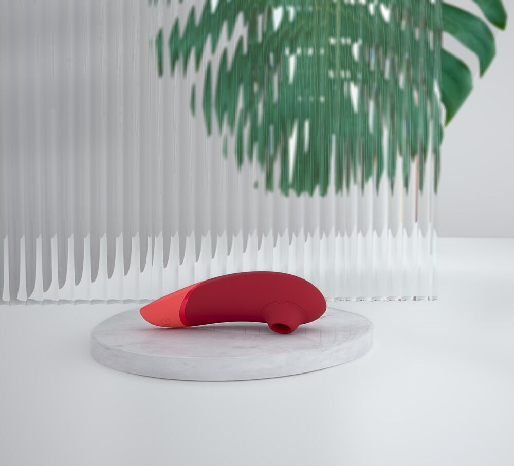 Roter Erotik-Vibrator mit abgerundetem Kopf auf runder Ablage