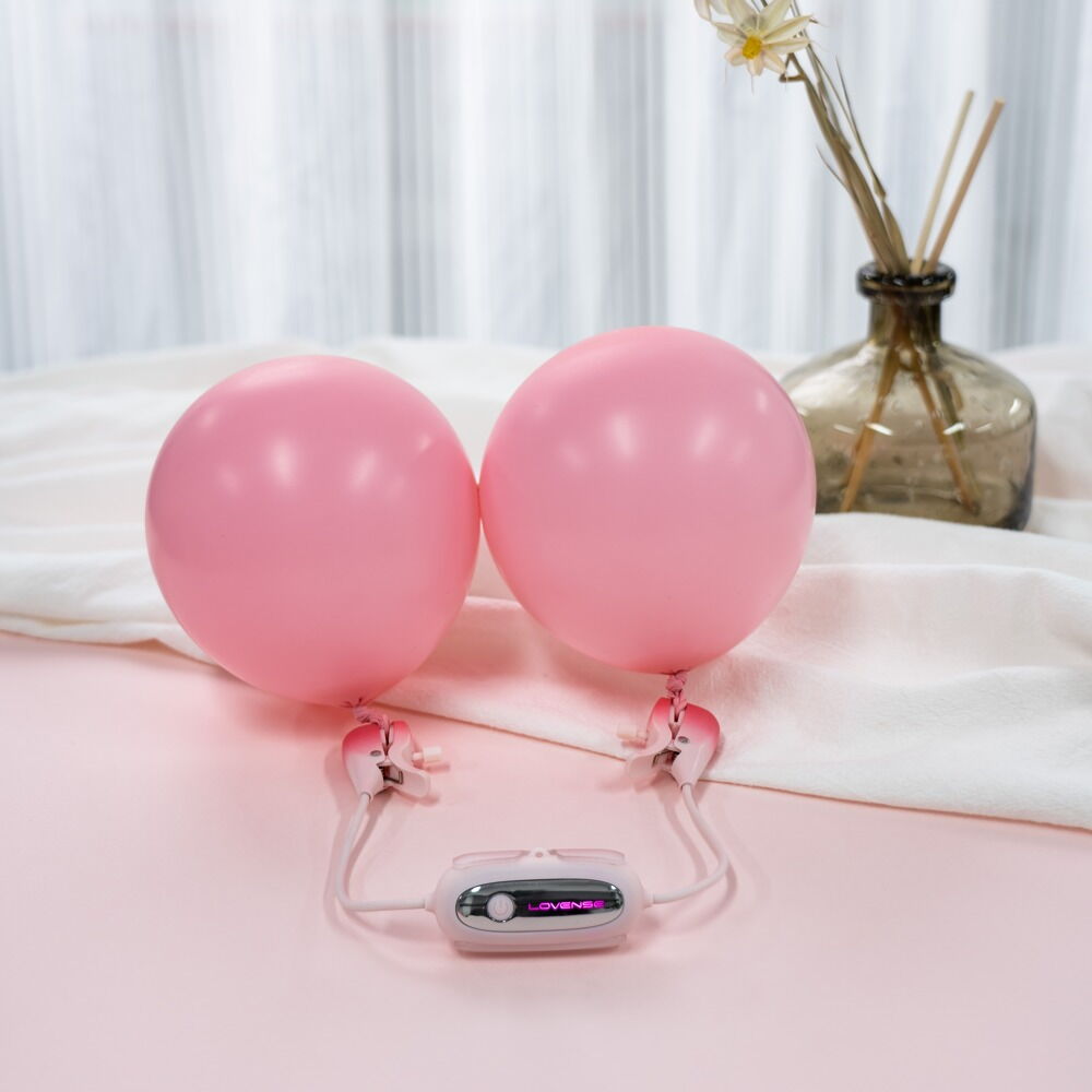 Paar pinke Nippelklemmen mit Bedieneinheit und angeschlossenem Kabel