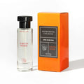 Duftkölner in Glasflasche mit schwarzem Deckel und orangefarbener Schachtel