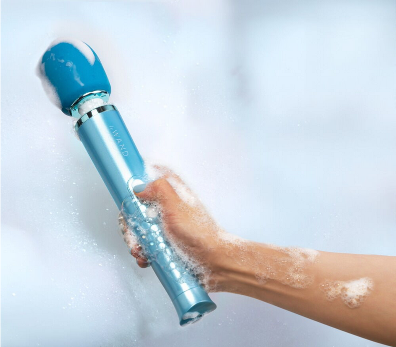 Unterwasser-Massagegerät türkisblau am Arm im Schaum, Düse aktiv