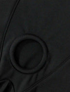 Nahaufnahme: Rundes Metall-/Kunststoffteil am Schritt einer schwarzen Harness-Short