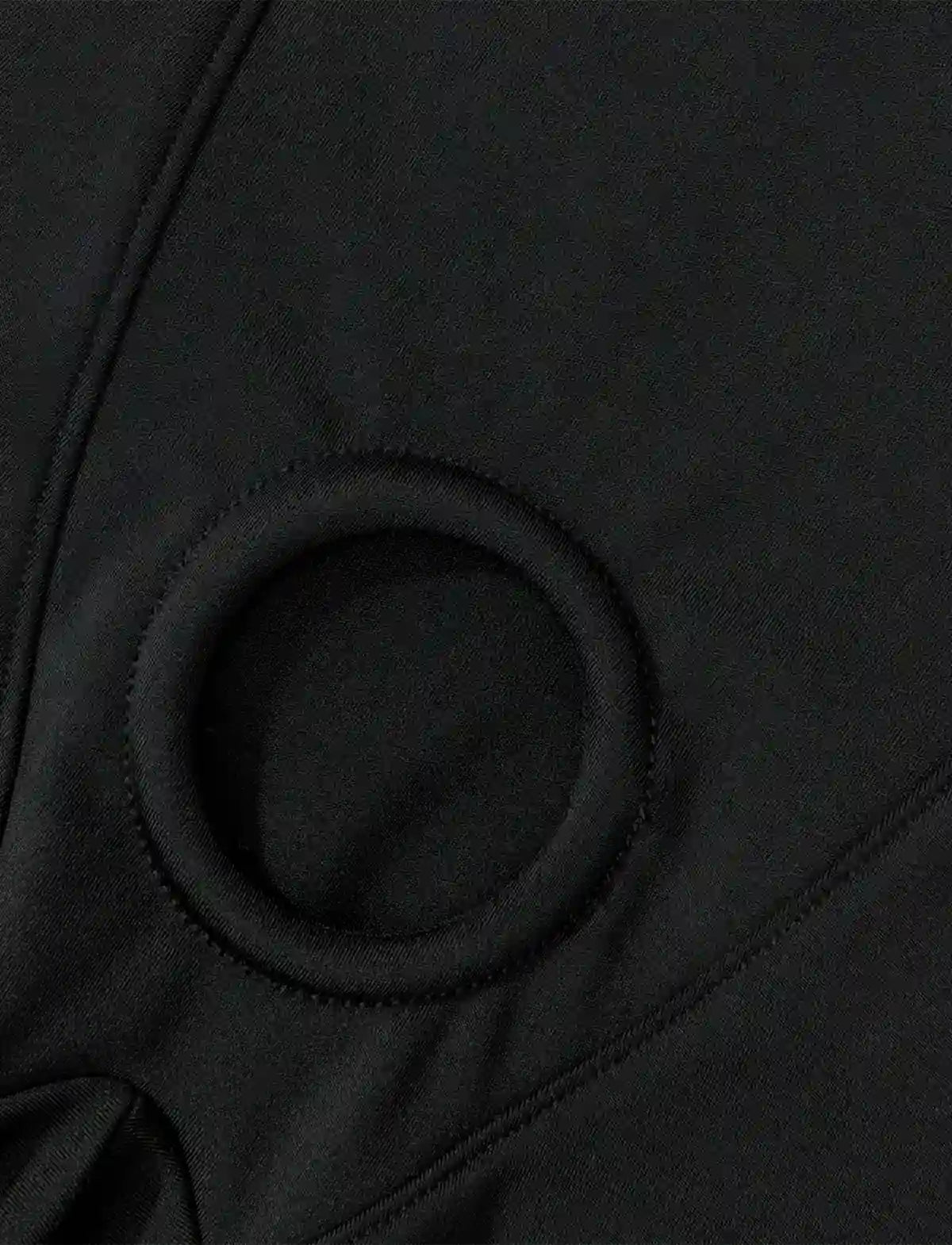Nahaufnahme: Rundes Metall-/Kunststoffteil am Schritt einer schwarzen Harness-Short
