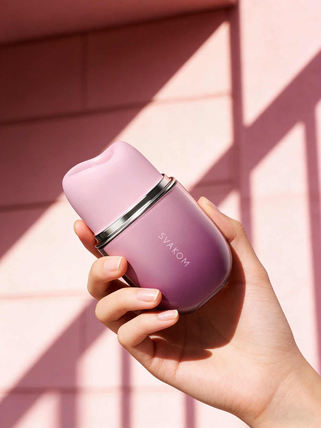 Hand hält Auflegevibrator SVAKOM Klitty in violettem Gehäuse mit silbernem Ring